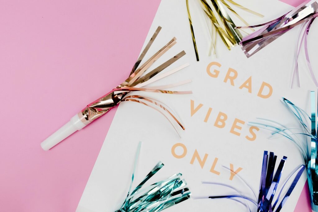 Sunroom Hosting Ideas for Mother’s Day & Graduation A party horn with metallic streamers and a sign that says GRAD VIBES ONLY on a pink background, surrounded by colorful metallic party decorations